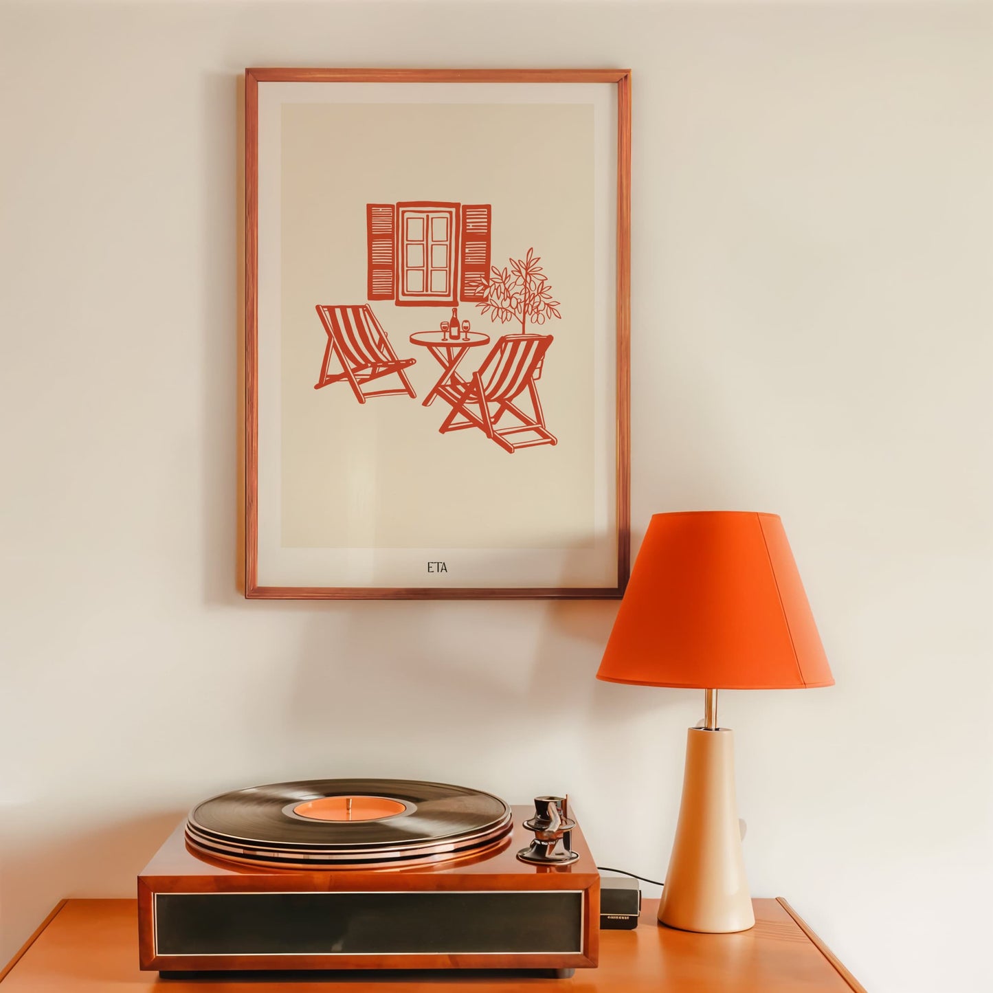 Wooden record player on a table with a framed print and orange lamp in the background.